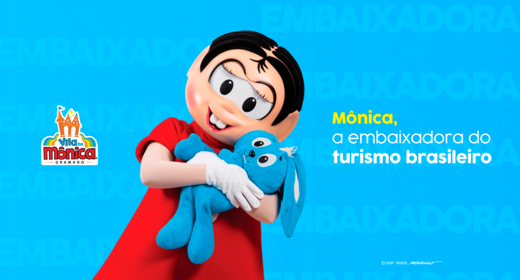 Personagem Mônica abraçando sua pelúcia Sansão, com os dizeres Mônica, a embaixadora do turismo brasileiro ao lado direito