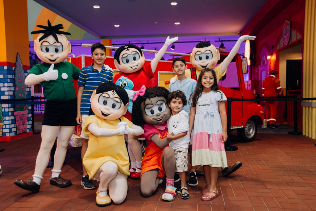 Crédito: Flávio Rodrigues [Descrição da imagem: Os personagens Cebolinha, Mônica, Cascão, Magali e Milena posam com três meninos e uma menina.]