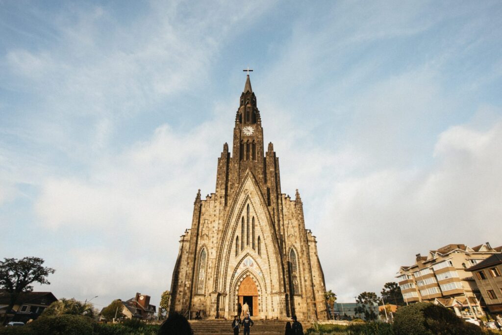 Crédito: Prefeitura de Canela/Divulgação [Descrição da imagem: A foto mostra, ao fundo, um céu azul claro com algumas nuvens. No primeiro plano, há uma igreja no estilo gótico.]